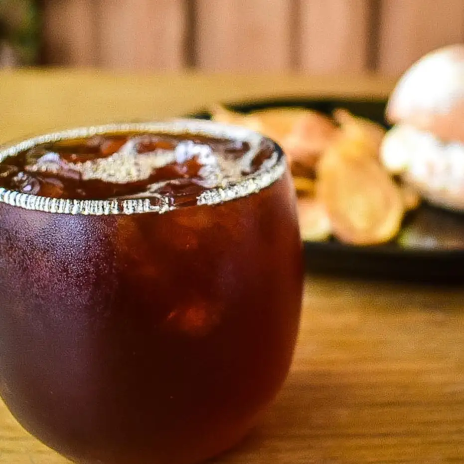 Café frío en vaso con borde de azúcar sobre una mesa de madera