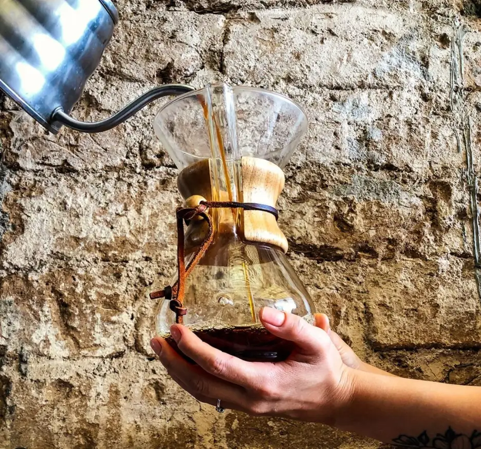 Café filtrado en Chemex servido frente a un muro de piedra