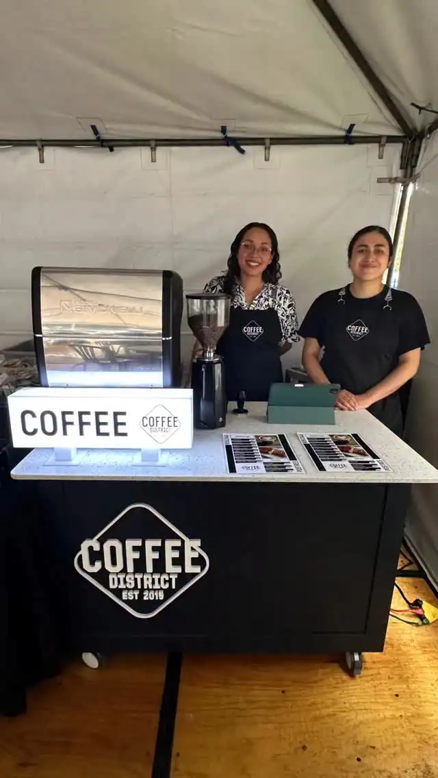 Barra móvil de Coffee District con dos baristas bajo una carpa en un evento