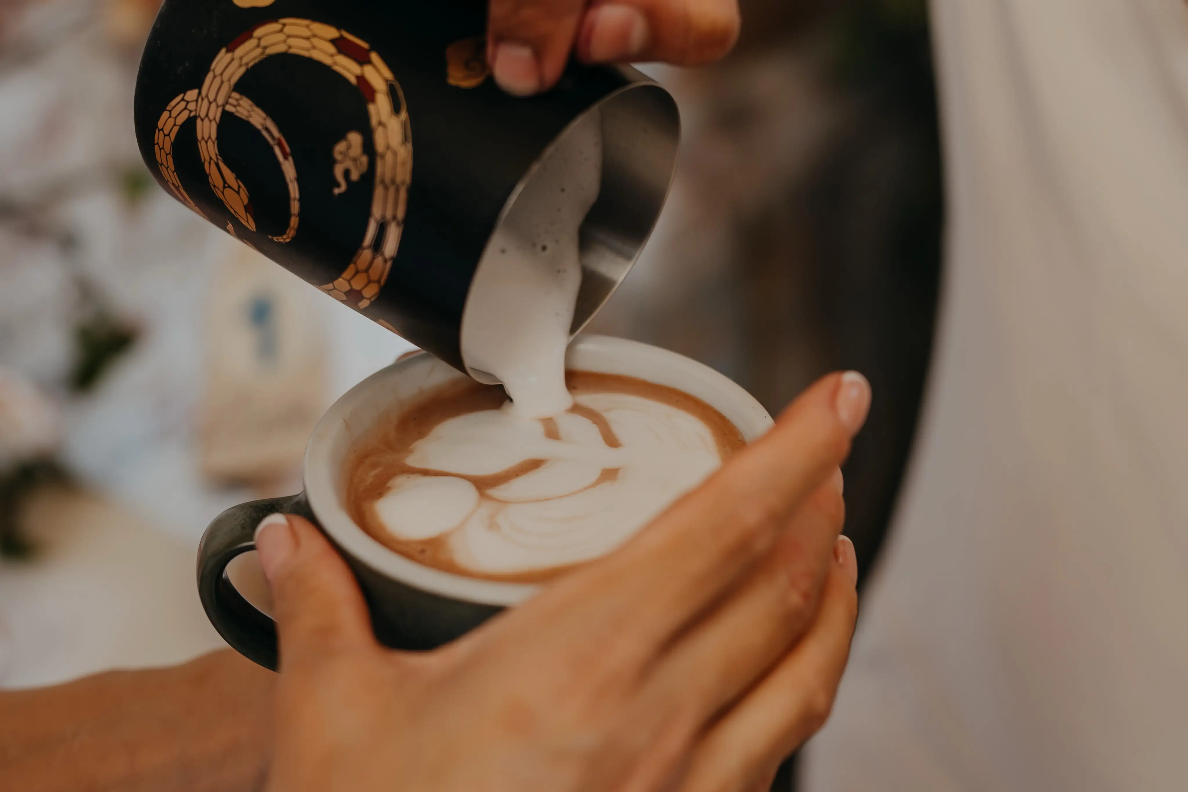 Barista vertiendo leche y dibujando arte latte en una taza