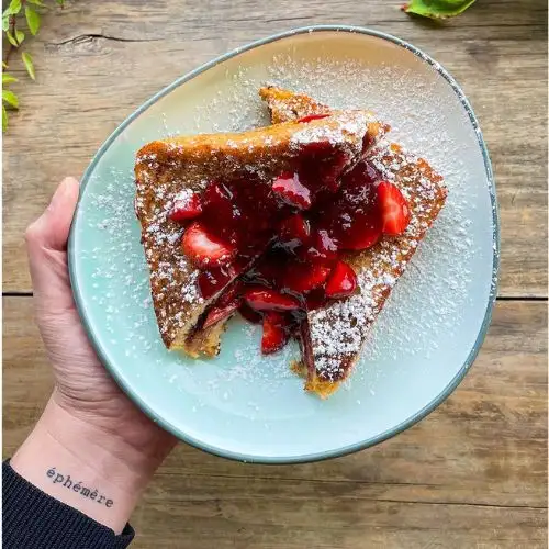 Tostada francesa con fresas y mermelada en un plato celeste